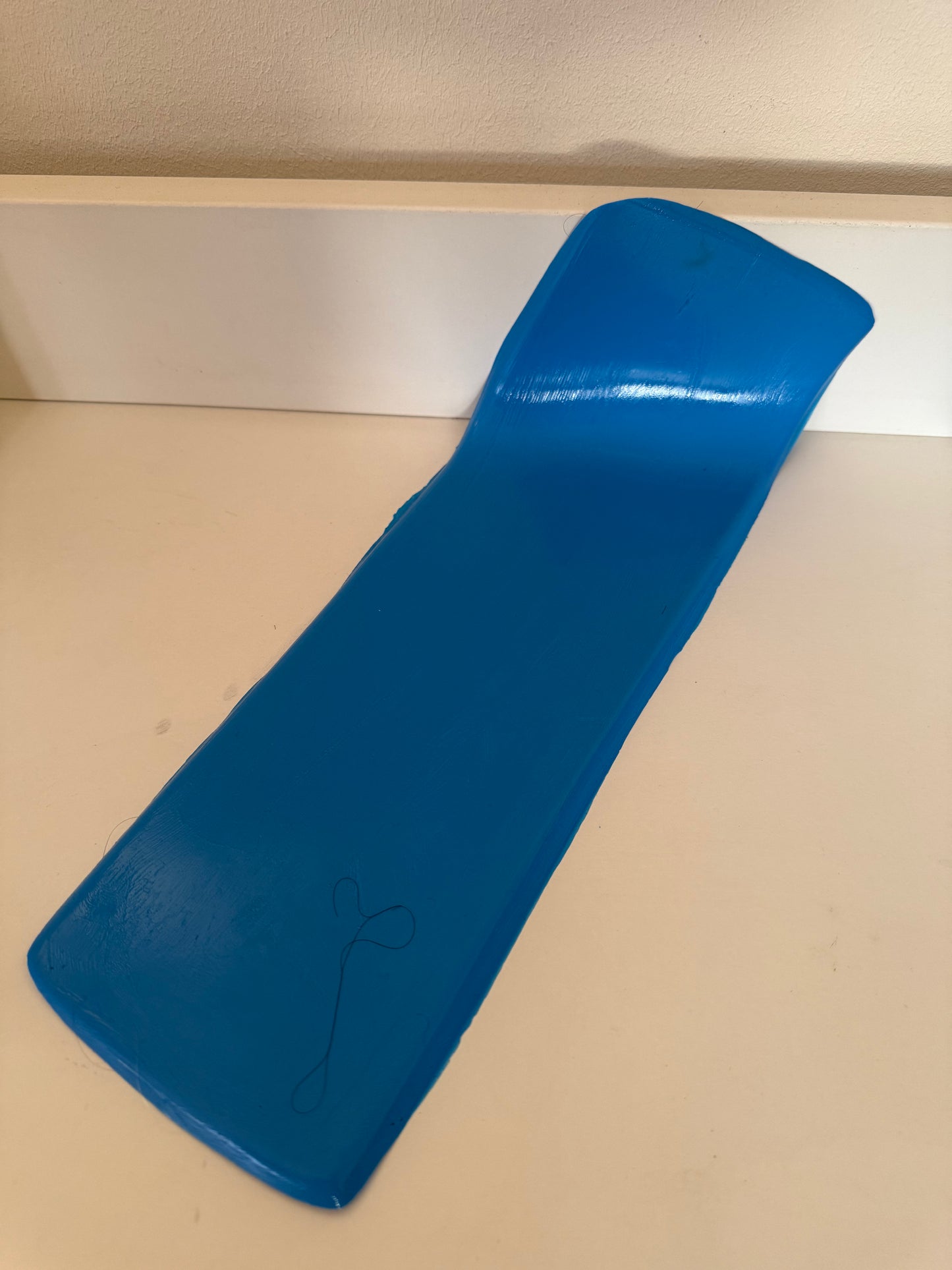 Support en caoutchouc incurvé pour l'injection de mèches de cheveux sur une micro-peau en vue de la fabrication de prothèses capillaires.