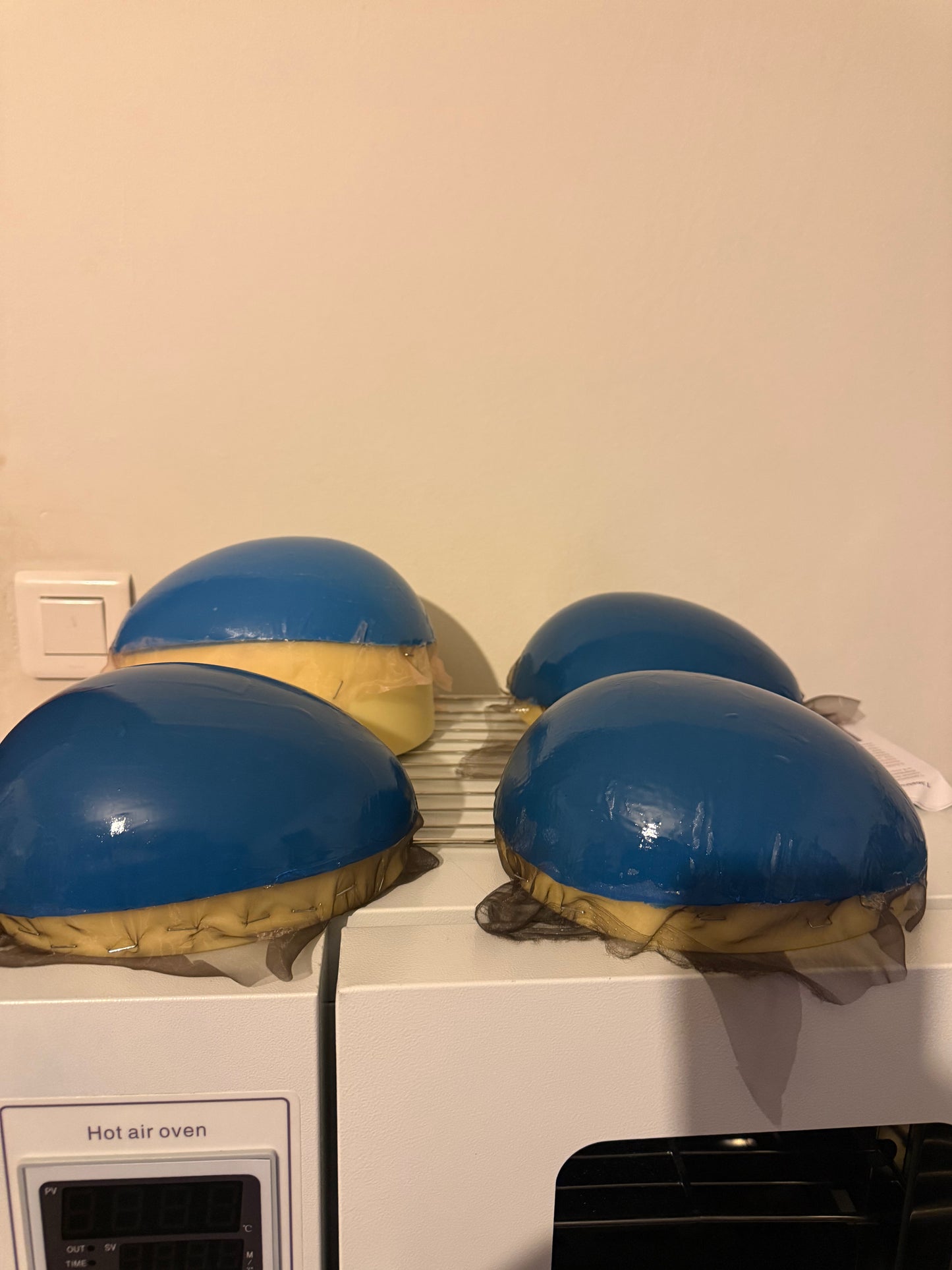 Support en caoutchouc incurvé pour l'injection de mèches de cheveux sur une micro-peau en vue de la fabrication de prothèses capillaires.