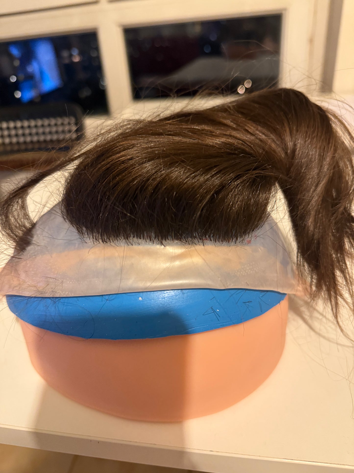 Support en caoutchouc incurvé pour l'injection de mèches de cheveux sur une micro-peau en vue de la fabrication de prothèses capillaires.