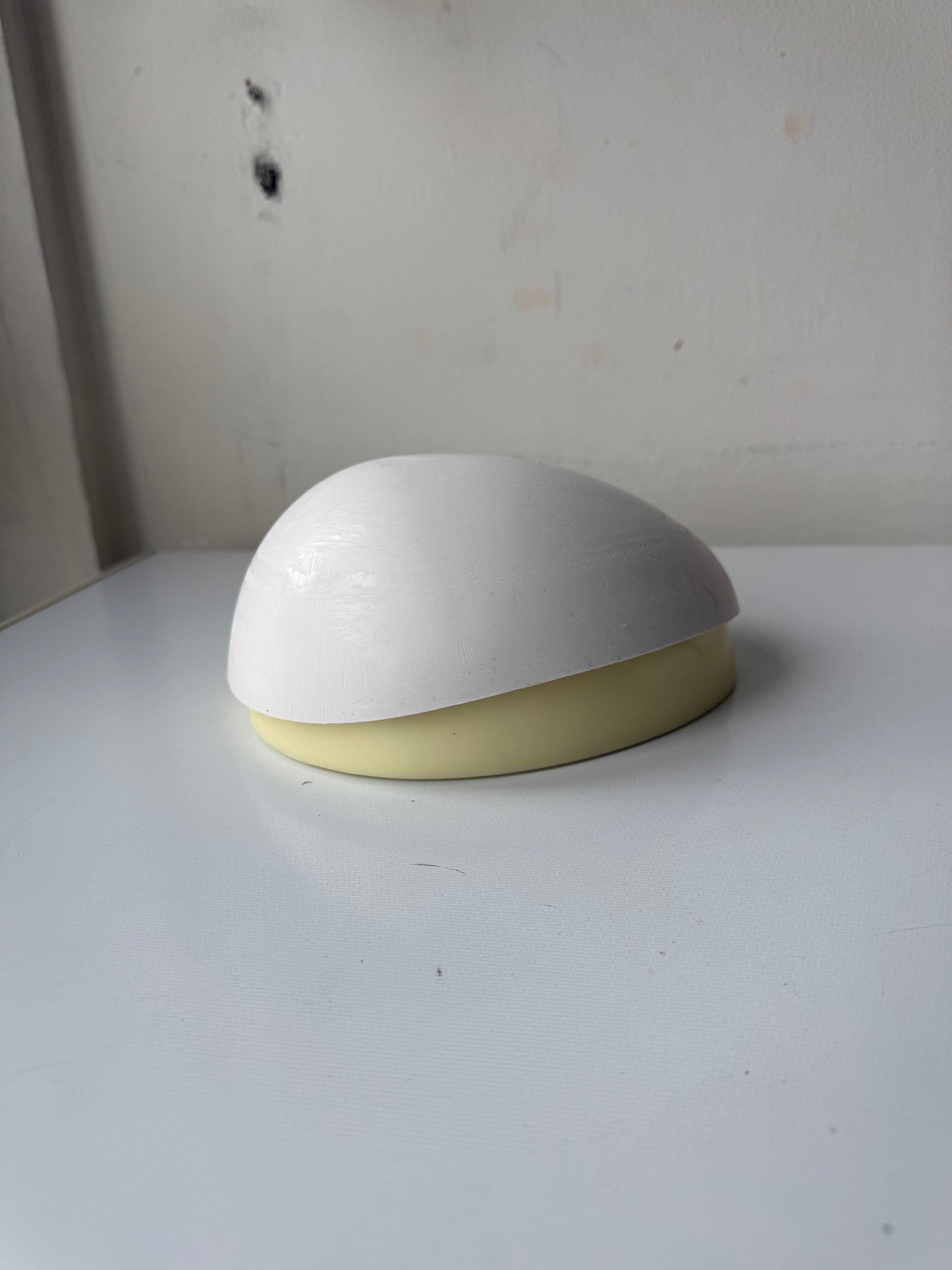 Support en caoutchouc incurvé pour l'injection de mèches de cheveux sur une micro-peau en vue de la fabrication de prothèses capillaires.